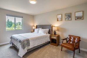 A bedroom with a bed, bedside lamps, a chair, and framed pictures on the wall. - 10 Min to Fairgrounds! Family Retreat in Puyallup (Puyallup)