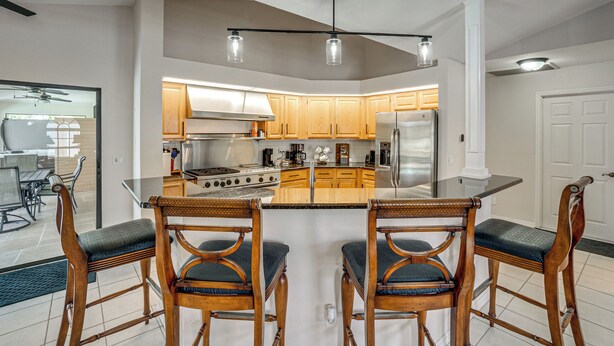 Una cocina moderna con armarios de madera, una isla central y un comedor con sillas de madera.