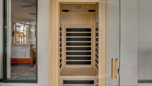 Una escalera de madera con una puerta de cristal que da a un dormitorio con cama y mesita de noche.
