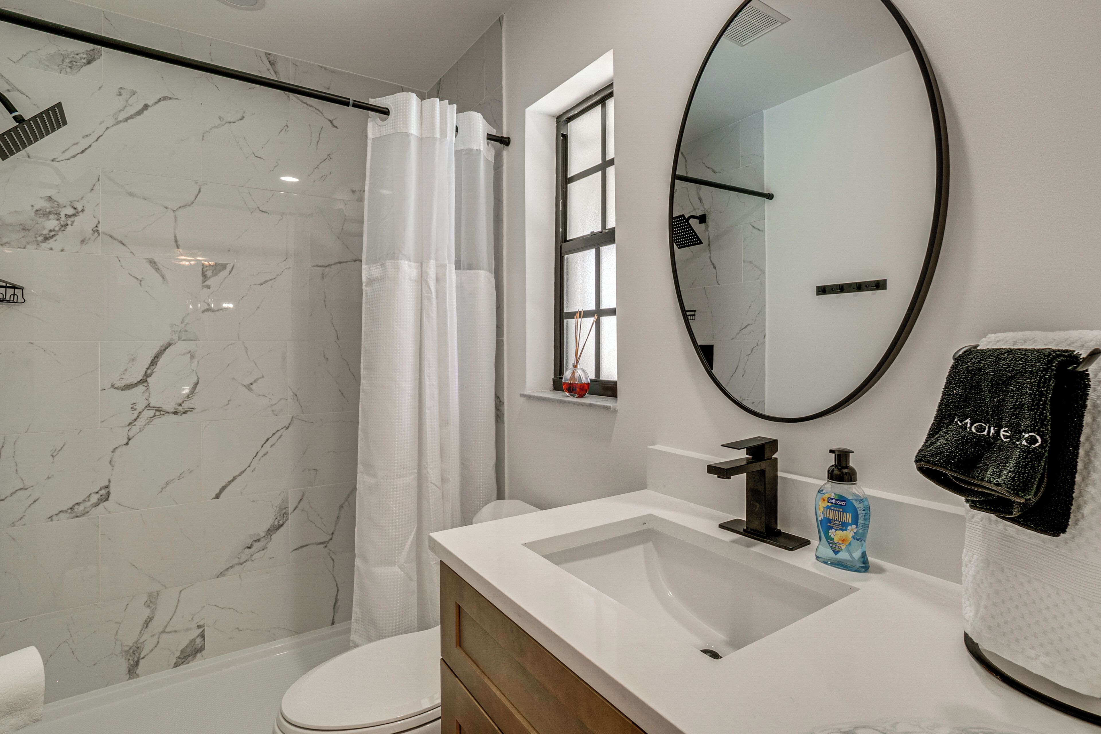 Un baño con ducha, inodoro, lavabo y espejo.