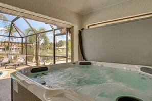 A hot tub with a view of palm trees and a pool area. - Luxury Oasis w/ Pool, Hot Tub, Dock & Sauna (Port Charlotte)