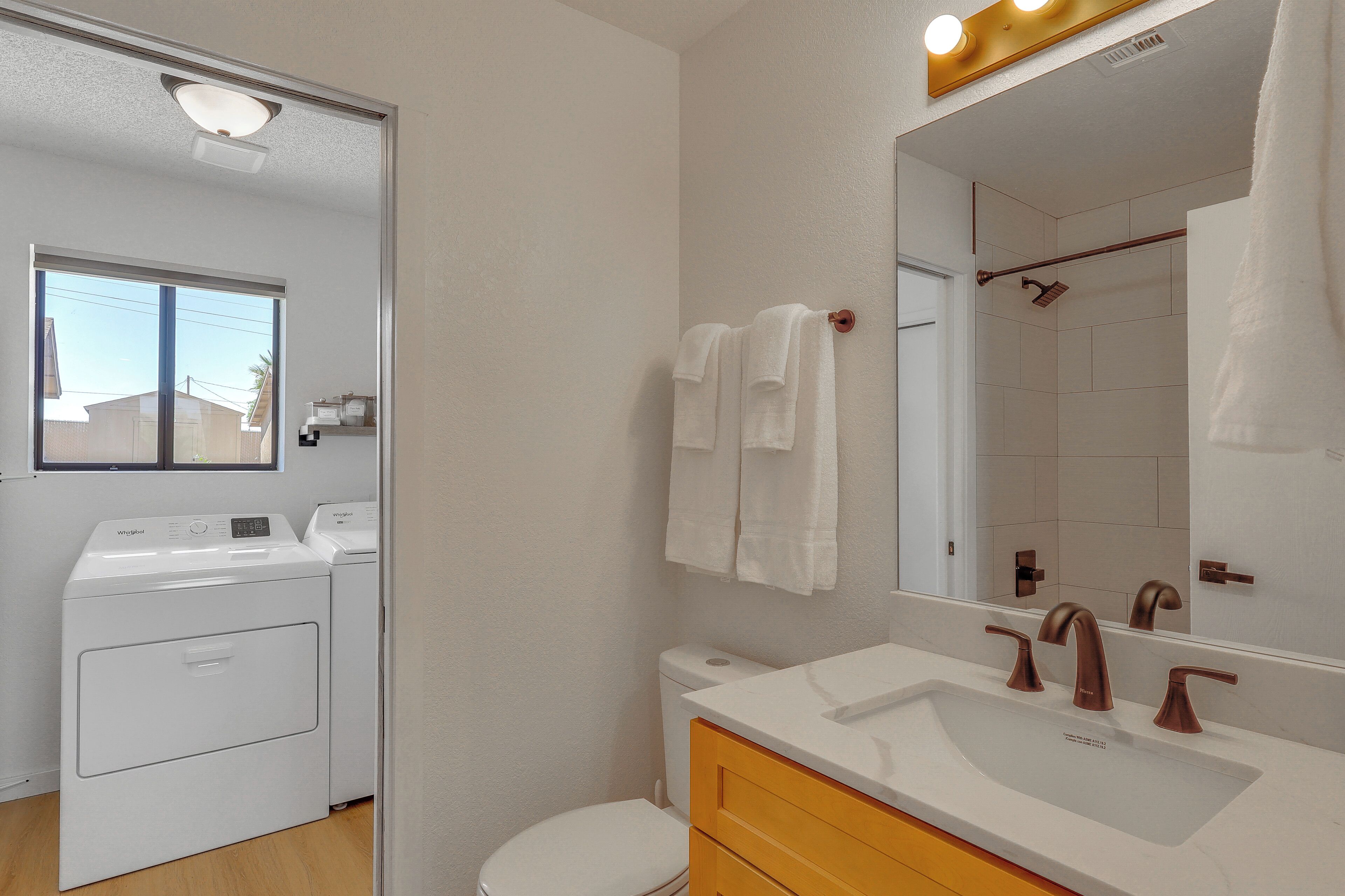 A bathroom with a white toilet, a sink with a mirror, and a washing machine.