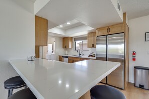 Uma cozinha moderna com uma ilha grande, eletrodomésticos de aço inoxidável e armários de madeira.