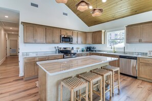 Cozinha moderna com armários de madeira, eletrodomésticos de aço inoxidável e uma ilha grande com banquetas.