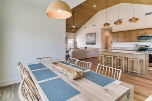 Una cocina amplia con armarios de madera, una isla central y elegantes lámparas colgantes.