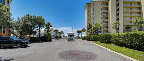 A multi-story hotel with a central courtyard, palm trees, and a clear blue sky.