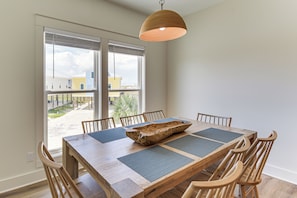 Ein Essbereich mit Holztisch, Stühlen und einem großen Fenster mit Jalousien.