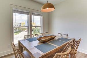 Un comedor con una mesa de madera, sillas y un ventanal con persianas.