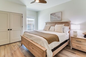 Un dormitorio con una cama de madera, una mesita de noche, una ventana y una puerta.