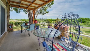 Un patio coperto con un tavolo e sedie in vetro, circondato da piante in vaso e vista sul paesaggio.
