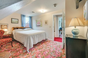 Un dormitorio con cama, una silla, una lámpara y una puerta que da a otra habitación.