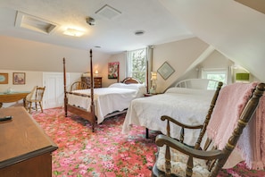 Un dormitorio con dos camas, un escritorio, una silla y una ventana.