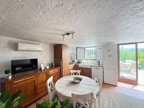 A compact kitchen with a dining table, a TV, and a refrigerator. - Apartment "L’échappée Provençale de Callian" with Mountain View, Wi-Fi, and Air Conditioning (Callian)