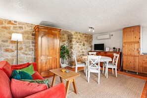 A living room with a red sofa, wooden cabinet, dining table, and chairs. - Apartment "L’échappée Provençale de Callian" with Mountain View, Wi-Fi, and Air Conditioning (Callian)