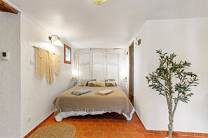A bedroom with a bed, a wall-mounted lamp, a plant, and a door. - Apartment "L’échappée Provençale de Callian" with Mountain View, Wi-Fi, and Air Conditioning (Callian)