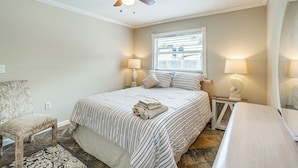 A bedroom with a bed, a chair, a nightstand with lamps, a ceiling fan, and a window with blinds. - Shop, Dine, Explore Dtwn! Punta Gorda Getaway (Punta Gorda)