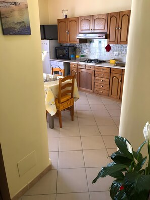 Uma cozinha com armários de madeira, uma mesa de jantar com cadeiras e um vaso com planta.
