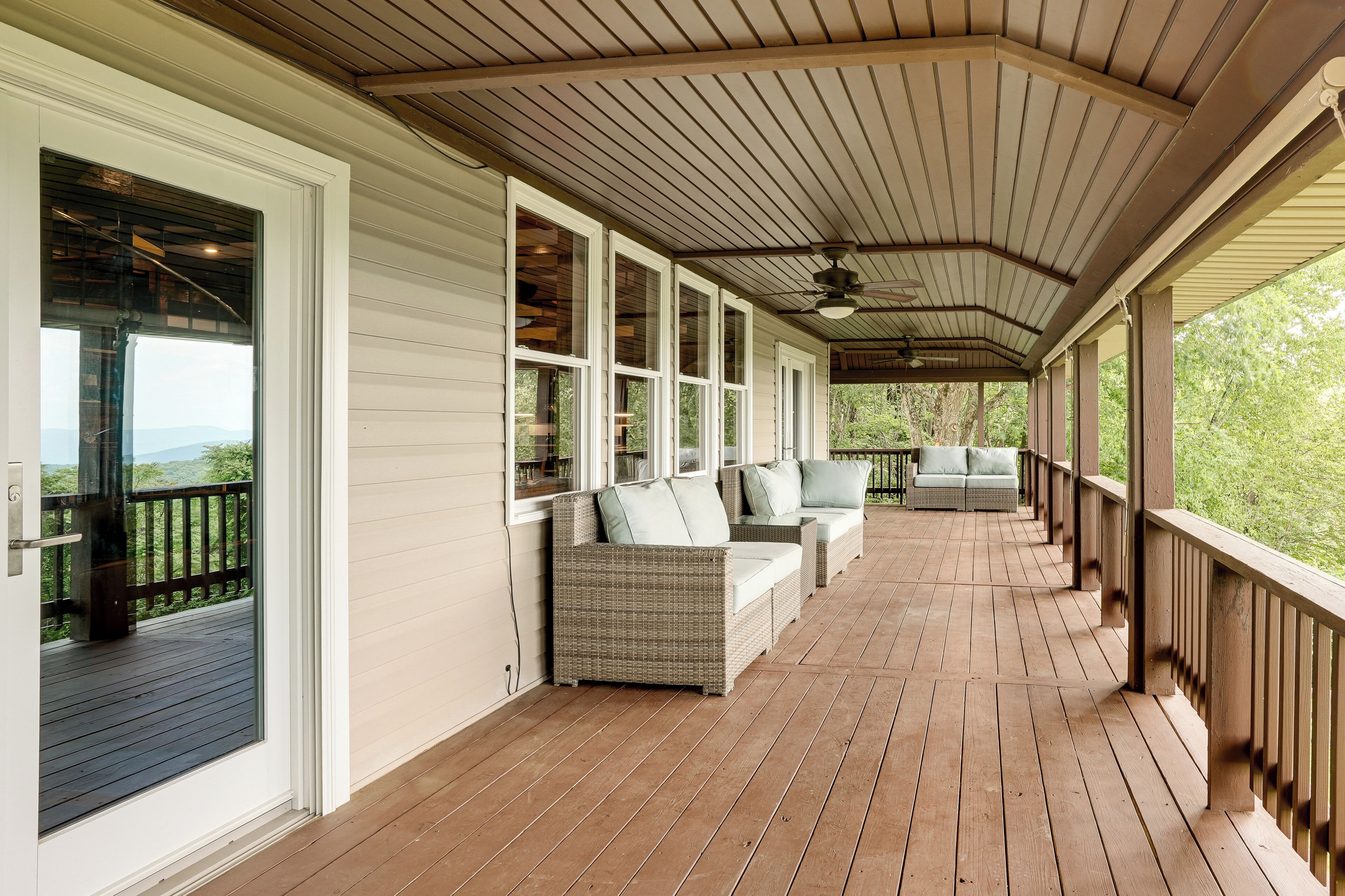 A covered porch with wooden flooring, white siding, and a ceiling fan.