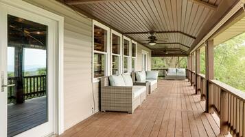 A covered porch with wooden flooring, white siding, and a ceiling fan.