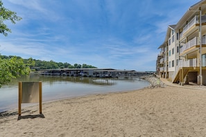 Ein Strandhotel mit Sandstrand, einem Holzstuhl und Blick auf Wasser und Steganlagen.