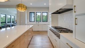 A modern kitchen with a large island, white cabinetry, and a gas stove. - Luxe Plymouth Group Getaway w/ Office & Foosball (Plymouth)