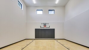 A basketball court with a hoop, two windows, and a wooden floor. - Luxe Plymouth Group Getaway w/ Office & Foosball (Plymouth)