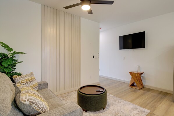 A modern living room with a sofa, ottoman, and a small table. - Near Dtwn & UT! Updated Knoxville Apartment (Knoxville)