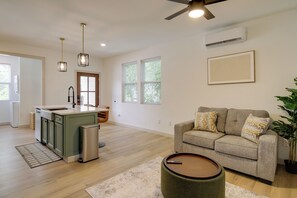 A modern living room with a sofa, a coffee table, and a kitchen area with a sink and cabinets. - Near Dtwn & UT! Updated Knoxville Apartment (Knoxville)