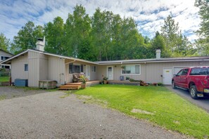 Ein eingeschossiges Gebäude mit einer überdachten Veranda, einer Garage und einer Schotterzufahrt.