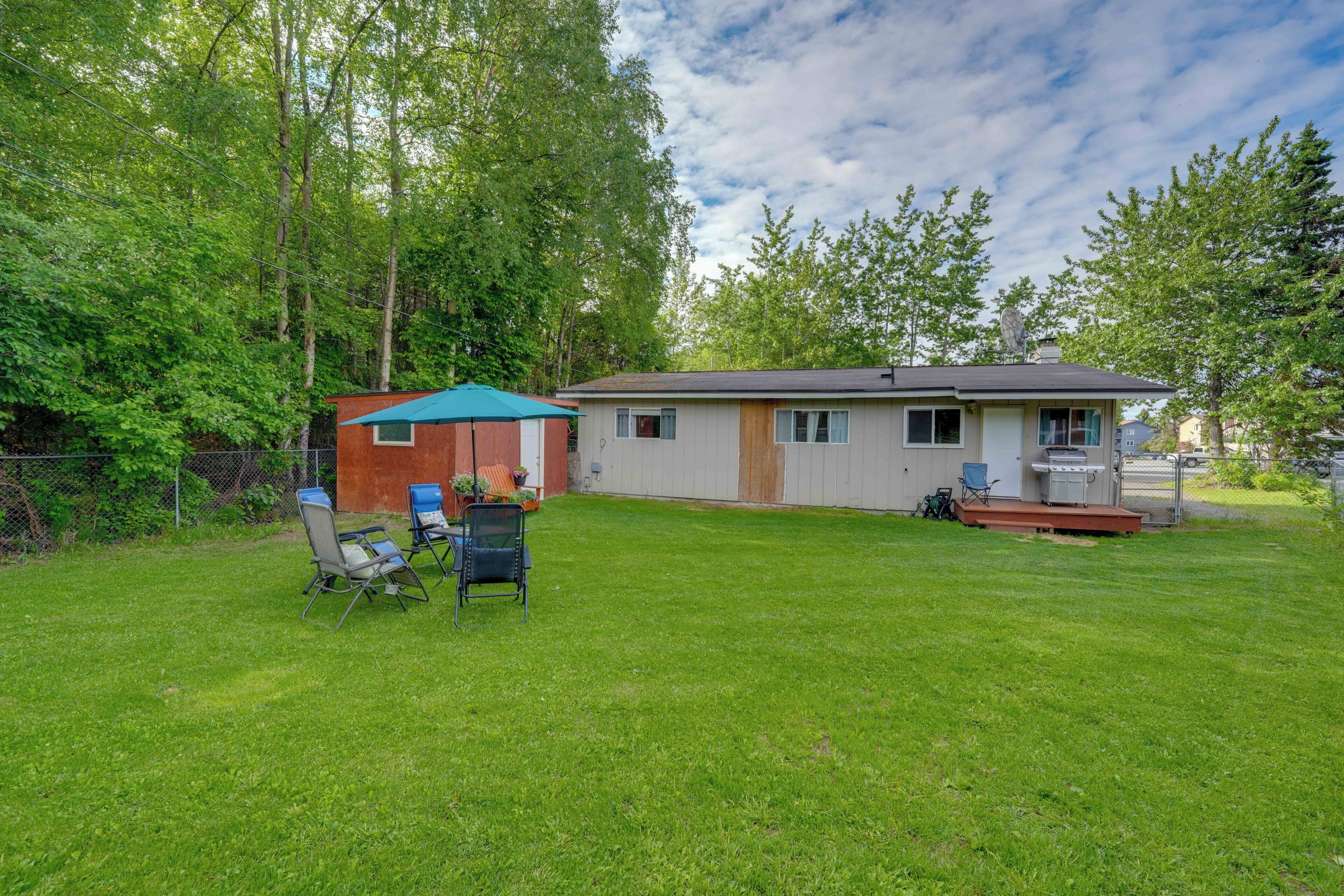 A single-story house with a fenced yard, a small porch, and a grill area.