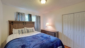 Ein Schlafzimmer mit Bett, Nachttisch, Lampe und Kleiderschrank.