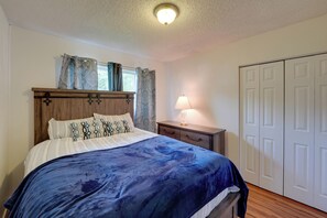 Ein Schlafzimmer mit Bett, Nachttisch, Lampe und Kleiderschrank.
