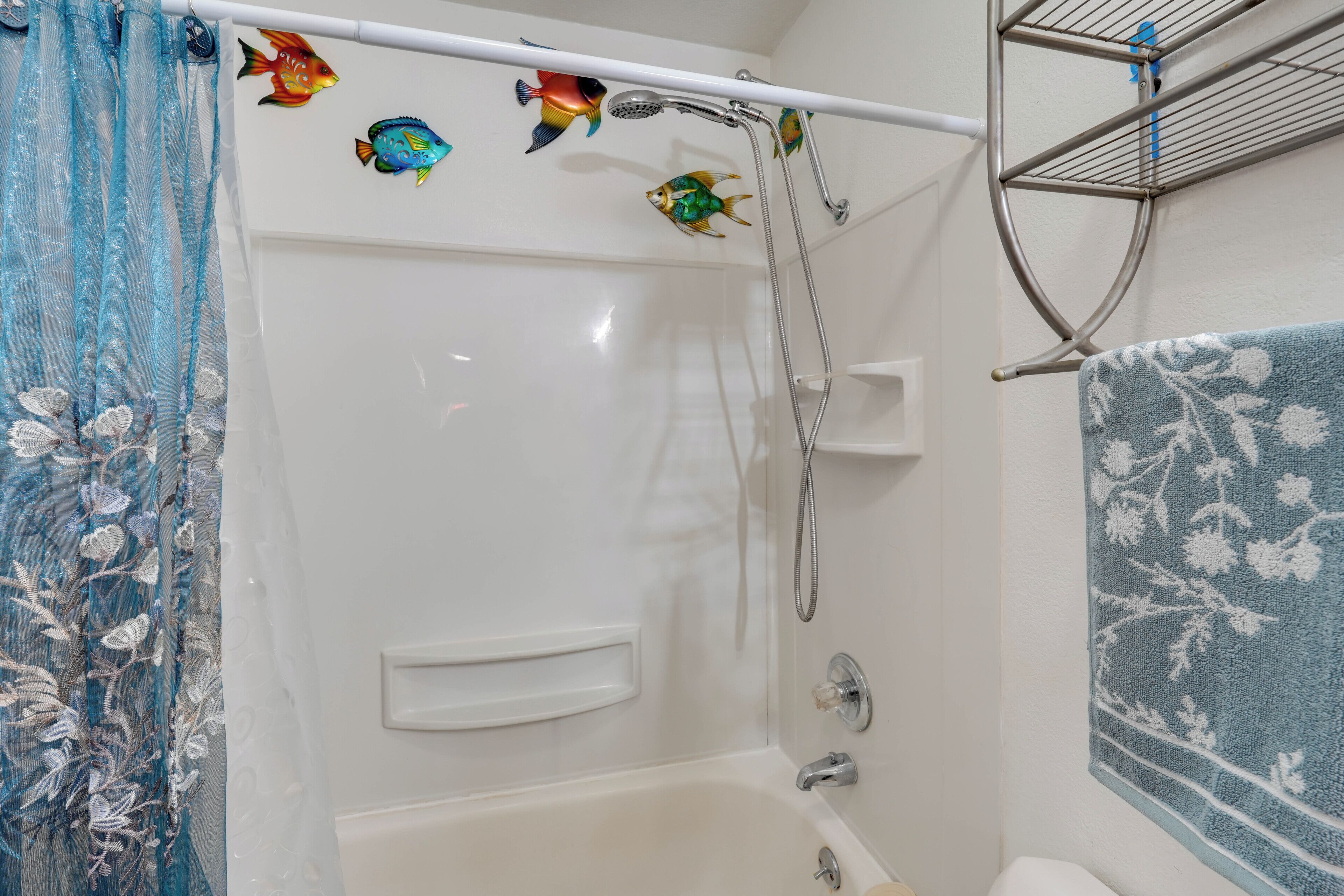 A bathroom with a bathtub, shower, and a towel rack.
