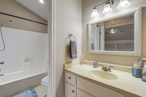 Un baño con bañera, lavamanos, espejo y ventilador de techo.