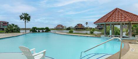A swimming pool with a chair, a gazebo, and a view of houses in the background.