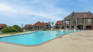 A swimming pool with lounge chairs and a wooden building with a red roof.