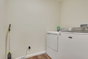 A laundry area with a washing machine and a mop leaning against the wall.
