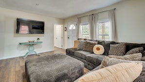 A living room with a sofa, ottoman, and a television mounted on the wall.