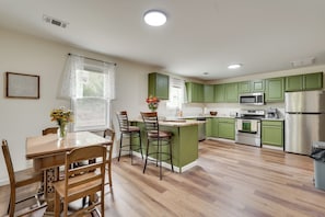 A kitchen with green cabinets, a wooden dining table, and a central island. - Historic Louisville Steps Away! Work & Play Home (Louisville)