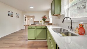 A kitchen with green cabinets, a white countertop, and a sink.