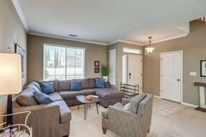 A living room with a sectional sofa, a round coffee table, and a grey armchair.