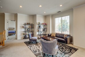 A living room with a sofa, armchairs, a coffee table, and bookshelves.