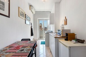 A compact kitchen with a dining area, a microwave, a kettle, and a small refrigerator. - 'Romaamor Casavacanze' Apartment with Private Terrace, Wi-Fi and Air Conditioning (Rome)