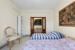 A bedroom with two beds, a chair, a wardrobe, a painting, and a door leading to another room. - 'Romaamor Casavacanze' Apartment with Private Terrace, Wi-Fi and Air Conditioning (Rome)