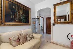 A room with a large classical painting, a sofa with patterned cushions, a mirror with an ornate frame, and a door leading to another room. - 'Romaamor Casavacanze' Apartment with Private Terrace, Wi-Fi and Air Conditioning (Rome)