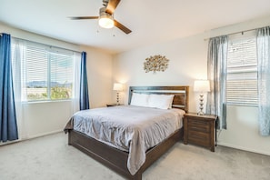 Ein Schlafzimmer mit Bett, Nachttischen, Deckenventilator und Wandbild.