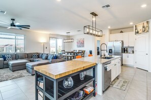 A modern kitchen with a central island, a dining area with a table and chairs, a living room with a sofa, and a ceiling fan. - Extended-stay Tucson Escape w/ Office & EV Charger (Tucson)