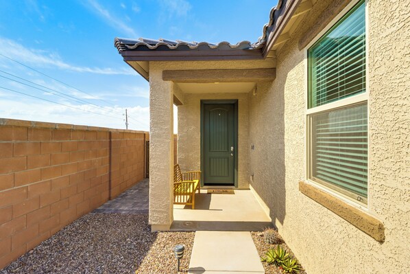 A house with a covered porch, a green door, and a window with blinds. - Extended-stay Tucson Escape w/ Office & EV Charger (Tucson)