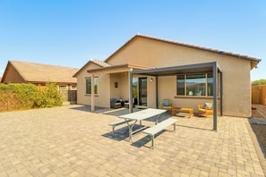 Ein Haus mit Terrasse, Sitzgelegenheiten im Freien und einer überdachten Fläche mit Tischen und Stühlen.