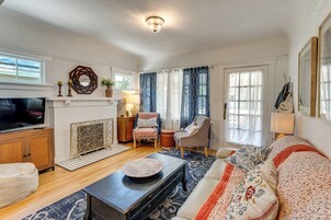 A living room with a fireplace, a sofa, a television, and a dining area.